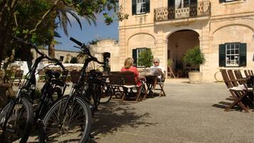 Un patio con bicicletas, mobiliario exterior y un edificio con arcos y balcones.