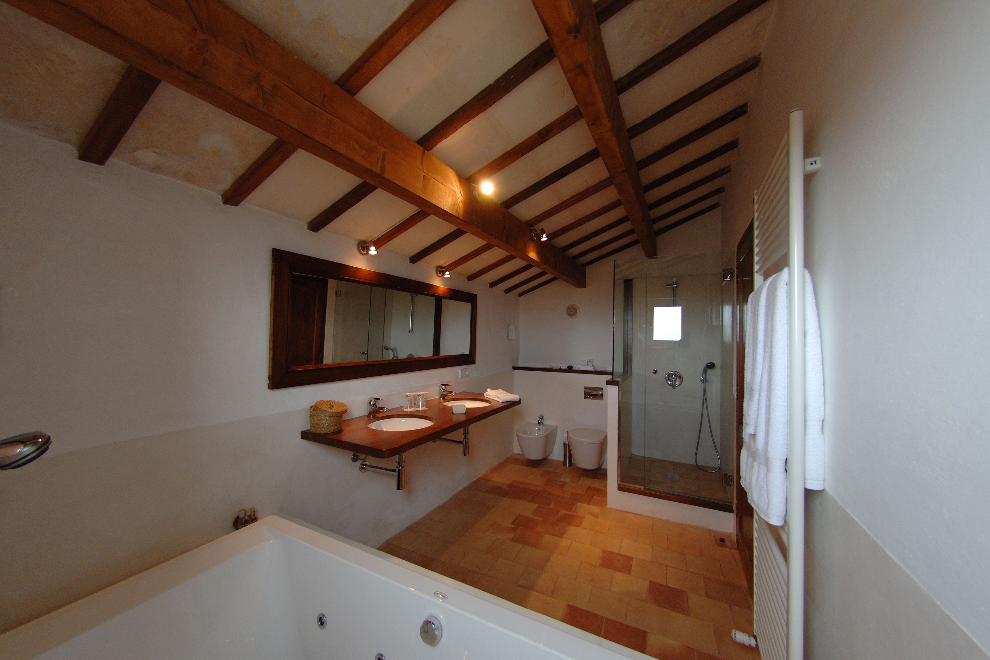 Un baño con bañera, dos lavamanos, un espejo grande y zona de ducha.