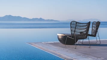 Relax by the pool in a tranquil setting surrounded by a calm body of water and distant mountains.