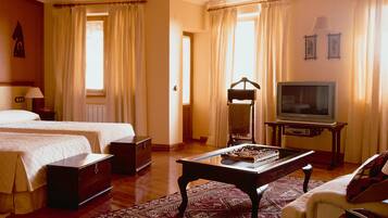 A hotel room with two beds, a television, a table with a decorative item, and a ceiling fan.
