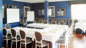 Een vergaderruimte met lange tafels, witte stoelen en blauwe wanden.