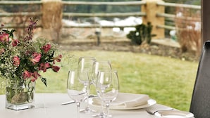 A table set for four with a vase of flowers, set against a backdrop of mountains and a rural landscape. - El Milano Real (Hoyos del Espino)