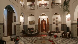 Un intérieur spacieux avec une fontaine centrale, de nombreux espaces de détente et un plafond haut agrémenté d’arches décoratives.