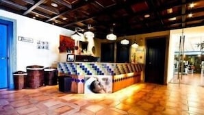 A reception area with a tiled floor, a counter with a patterned design, and a ceiling with exposed beams and hanging lights. - Apartamentos Bahía Santa Cruz (Almunecar)