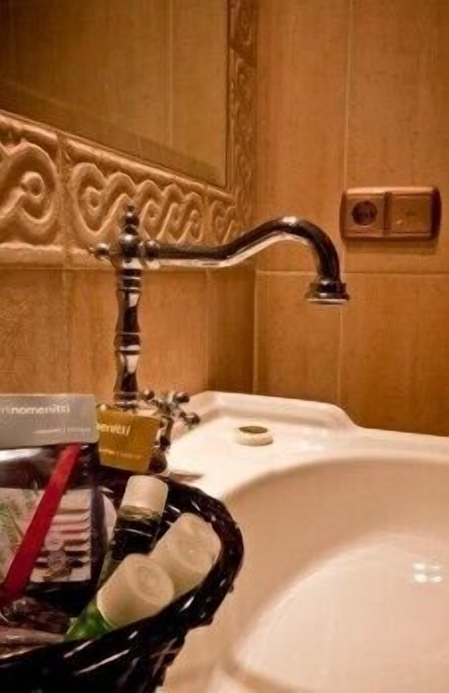 Un lavabo de baño con un panel decorativo en la pared y un grifo.