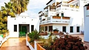 A modern building with a flat roof, multiple balconies, and a central entrance. - Apartamentos Bahía Santa Cruz (Almunecar)