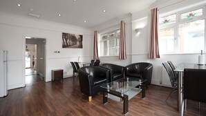 Una sala de estar moderna con sofás de cuero, una mesa de centro de vidrio y un comedor con sillas.