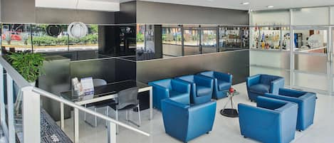 Una hall moderna con posti a sedere blu, una reception e vista sulla strada.