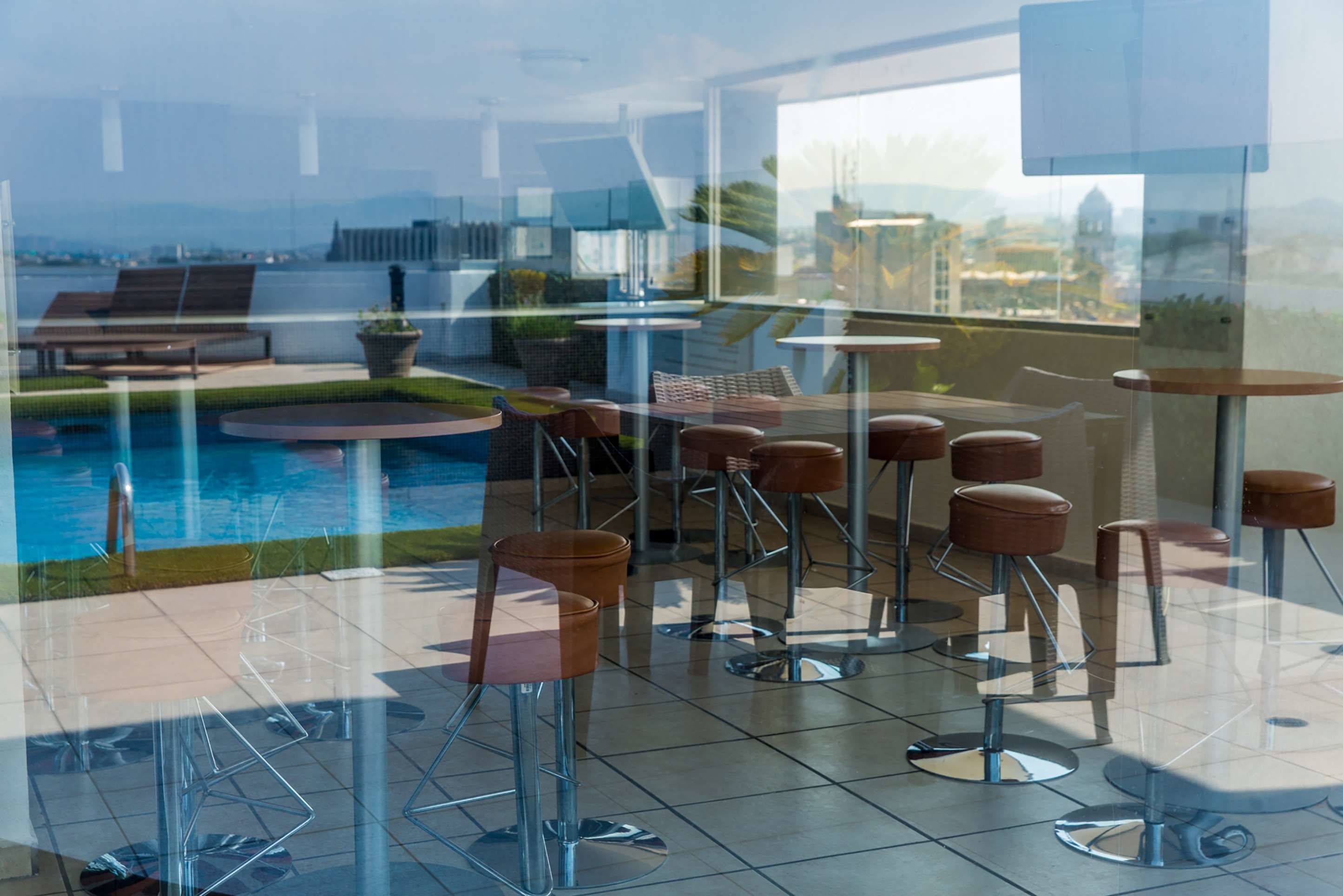 A modern bar area with high stools and a pool view.