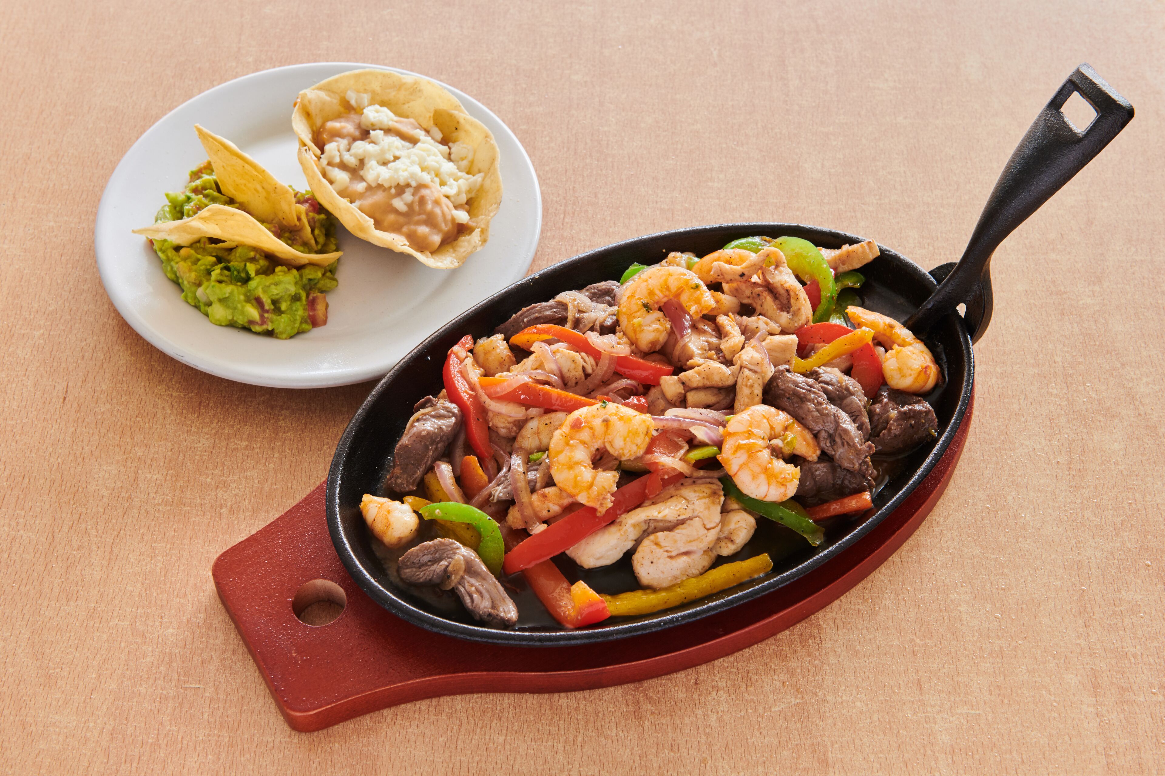 A skillet with a variety of food including shrimp, meat, and vegetables.