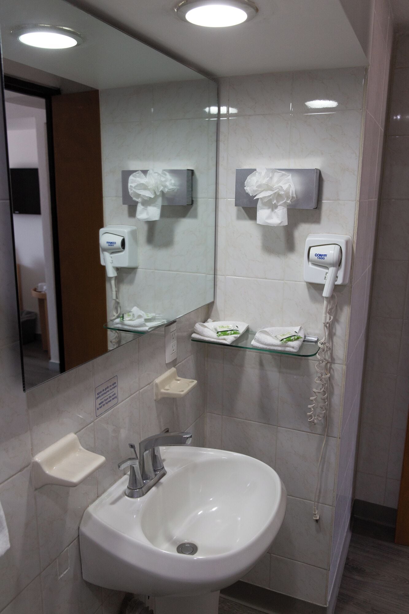 A modern bathroom with a white sink, a mirror, and two paper towel dispensers.