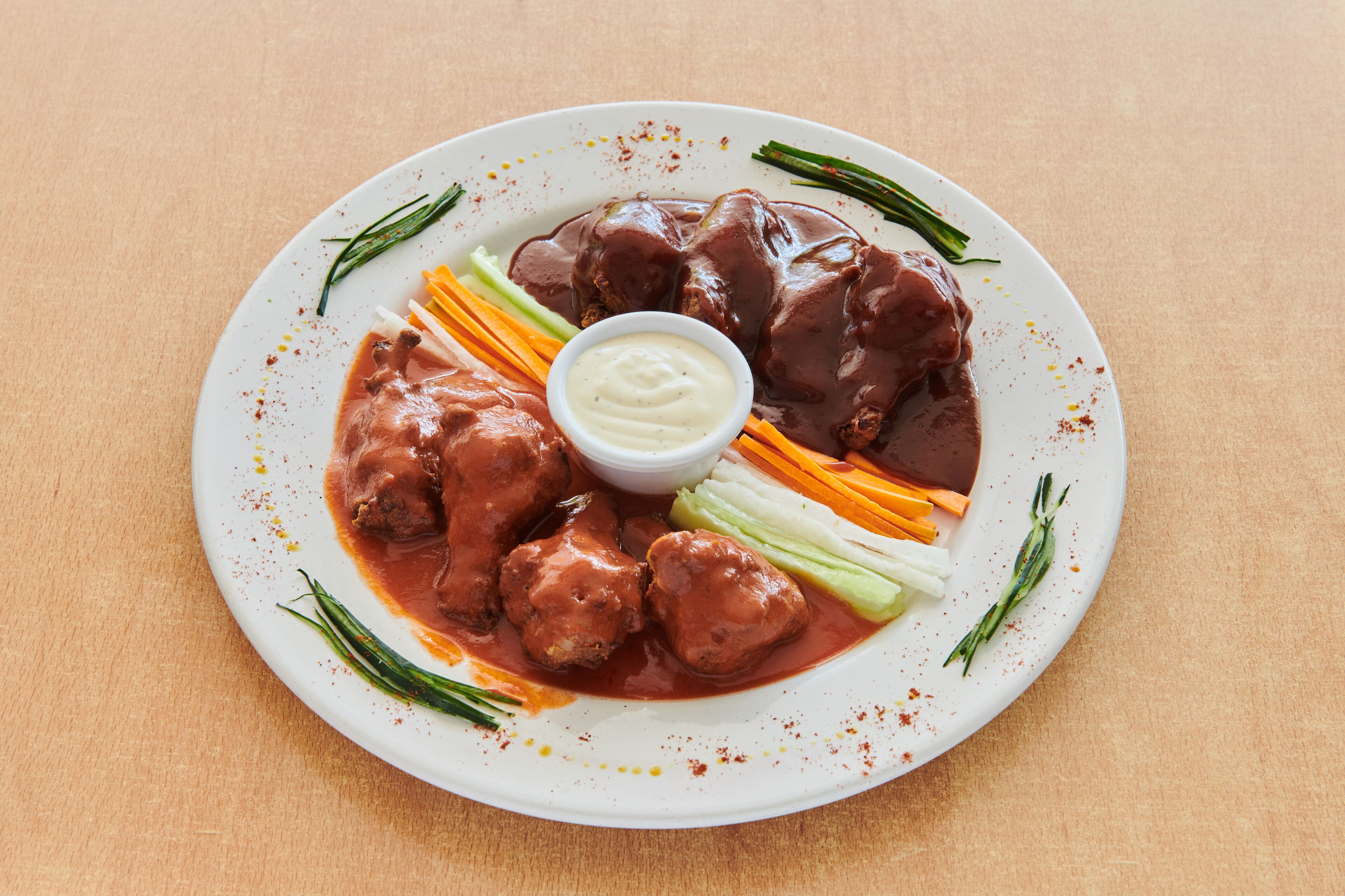 A plate of food with meatballs, vegetables, and a dipping sauce.