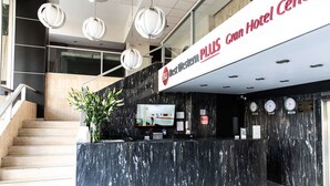 Zona de recepción de hotel con mostrador de mármol, una escalera y un cartel que dice "Best Western PLUS Gran Hotel Center".