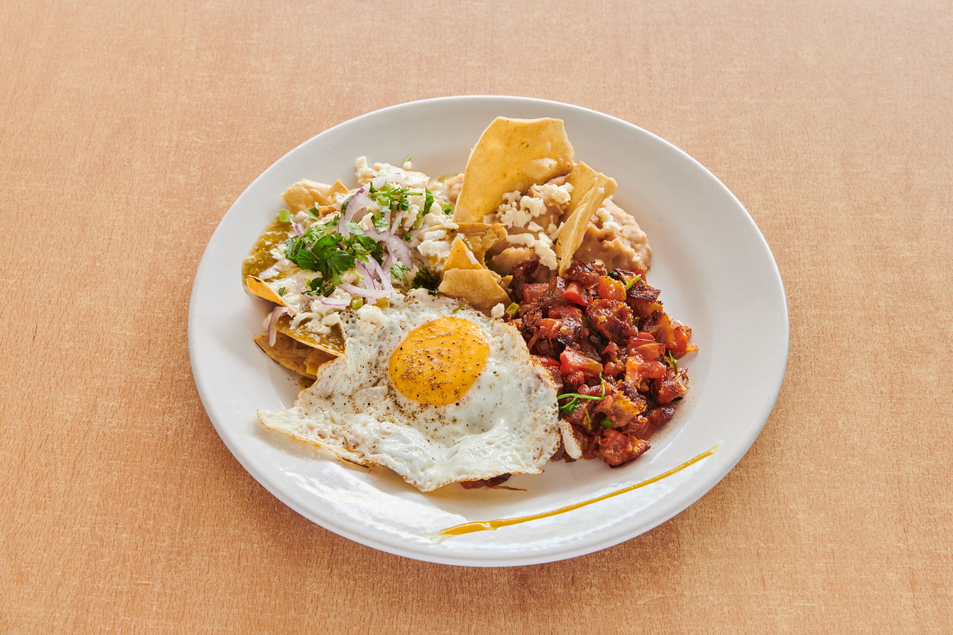 A plate of food with a fried egg, beans, and tortilla chips.