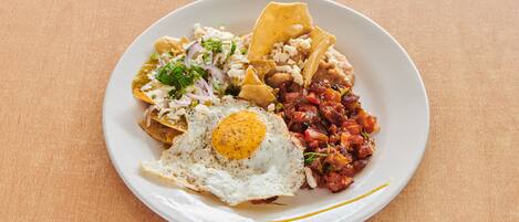 A plate of food with a fried egg, beans, and tortilla chips.