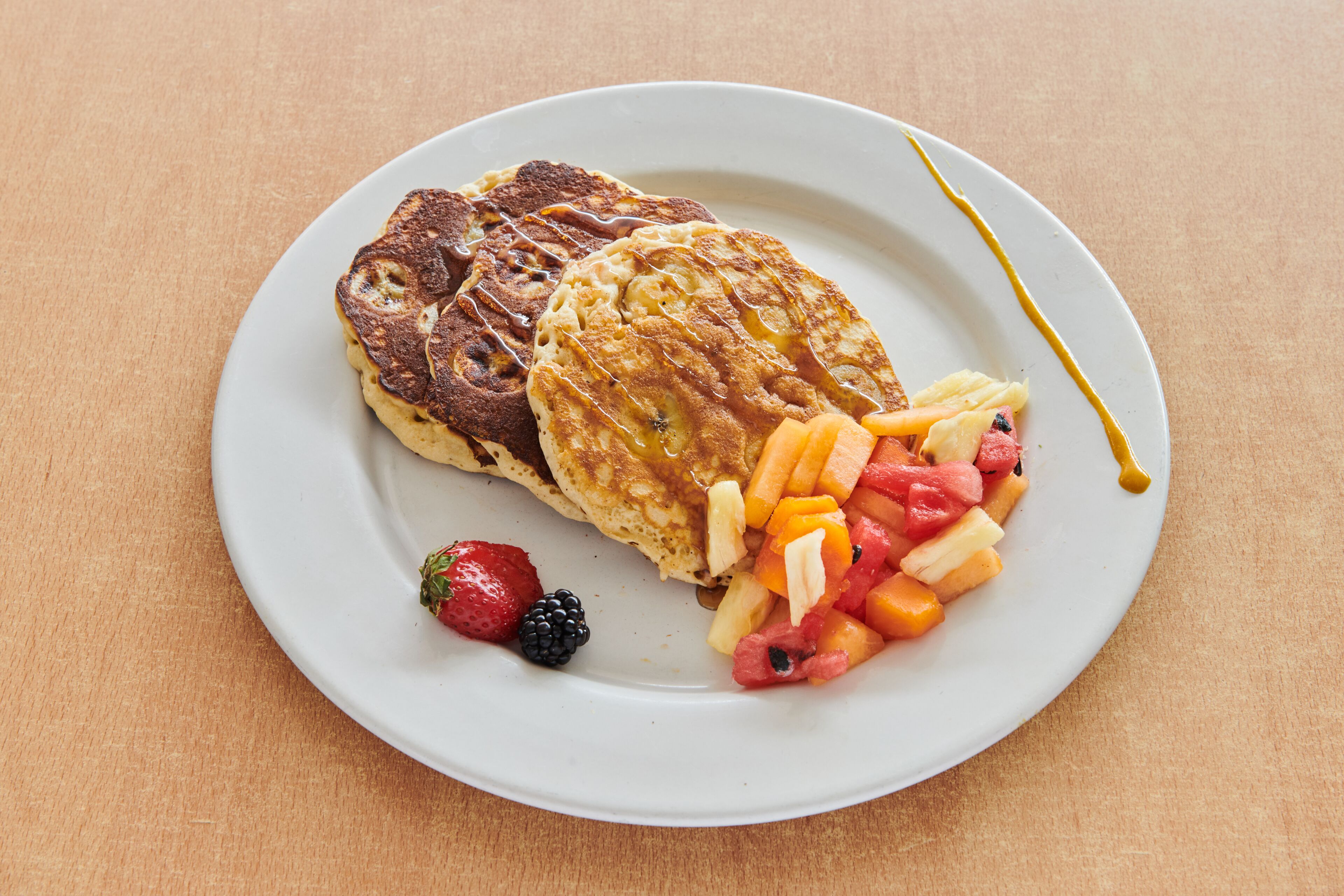 A plate with pancakes and fruit on a table.