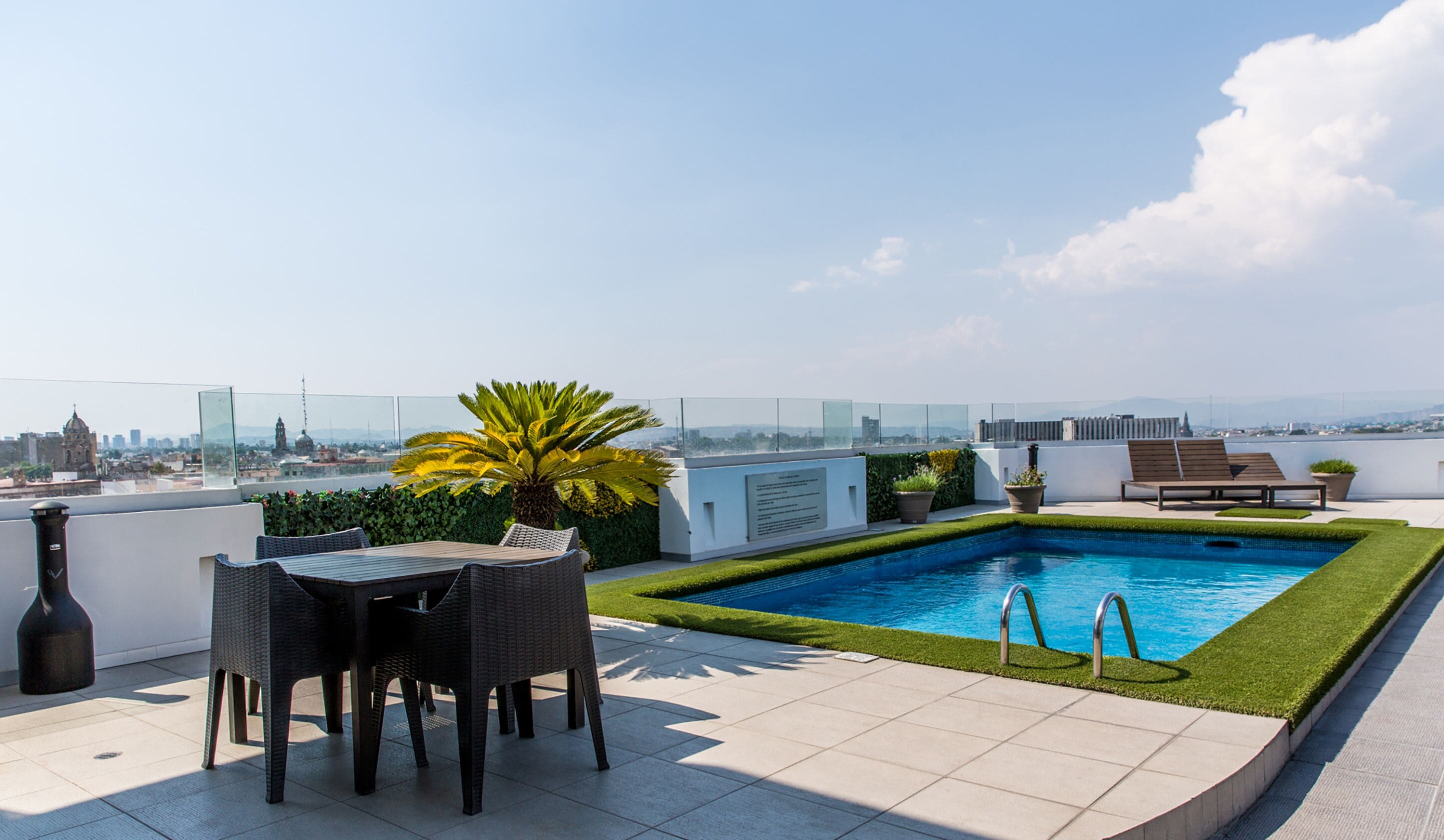 Terraza en la azotea con piscina, zona de estar y vistas a la ciudad.