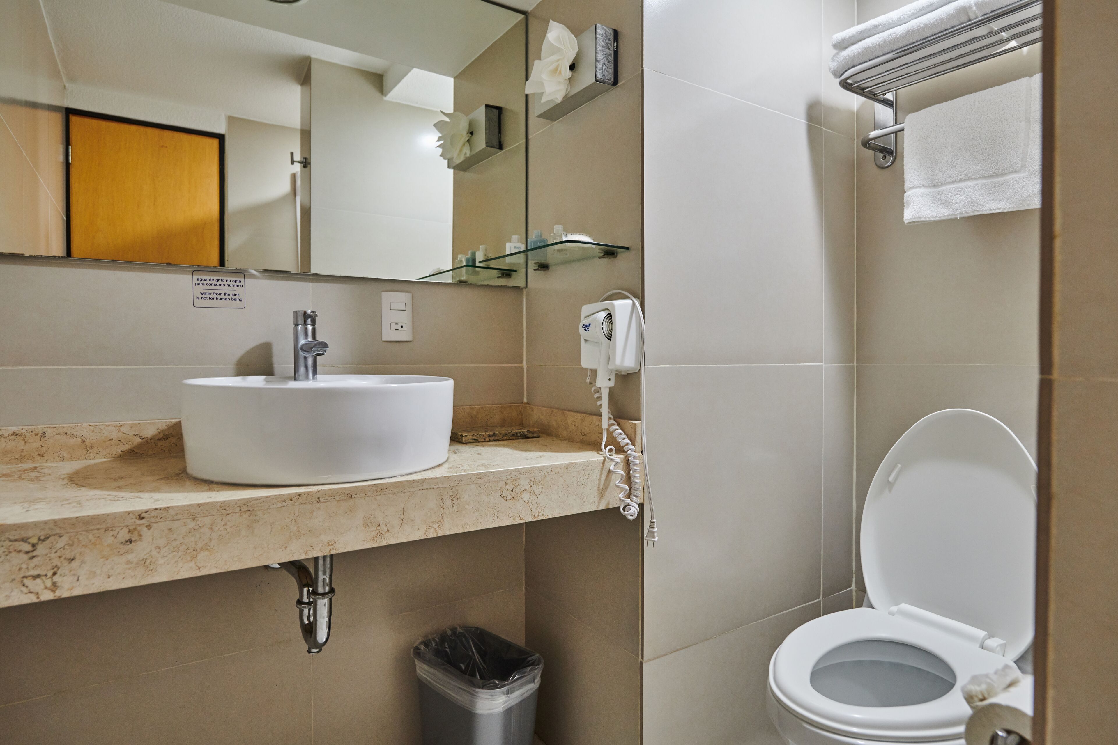 A bathroom with a sink, mirror, toilet, and towel rack.