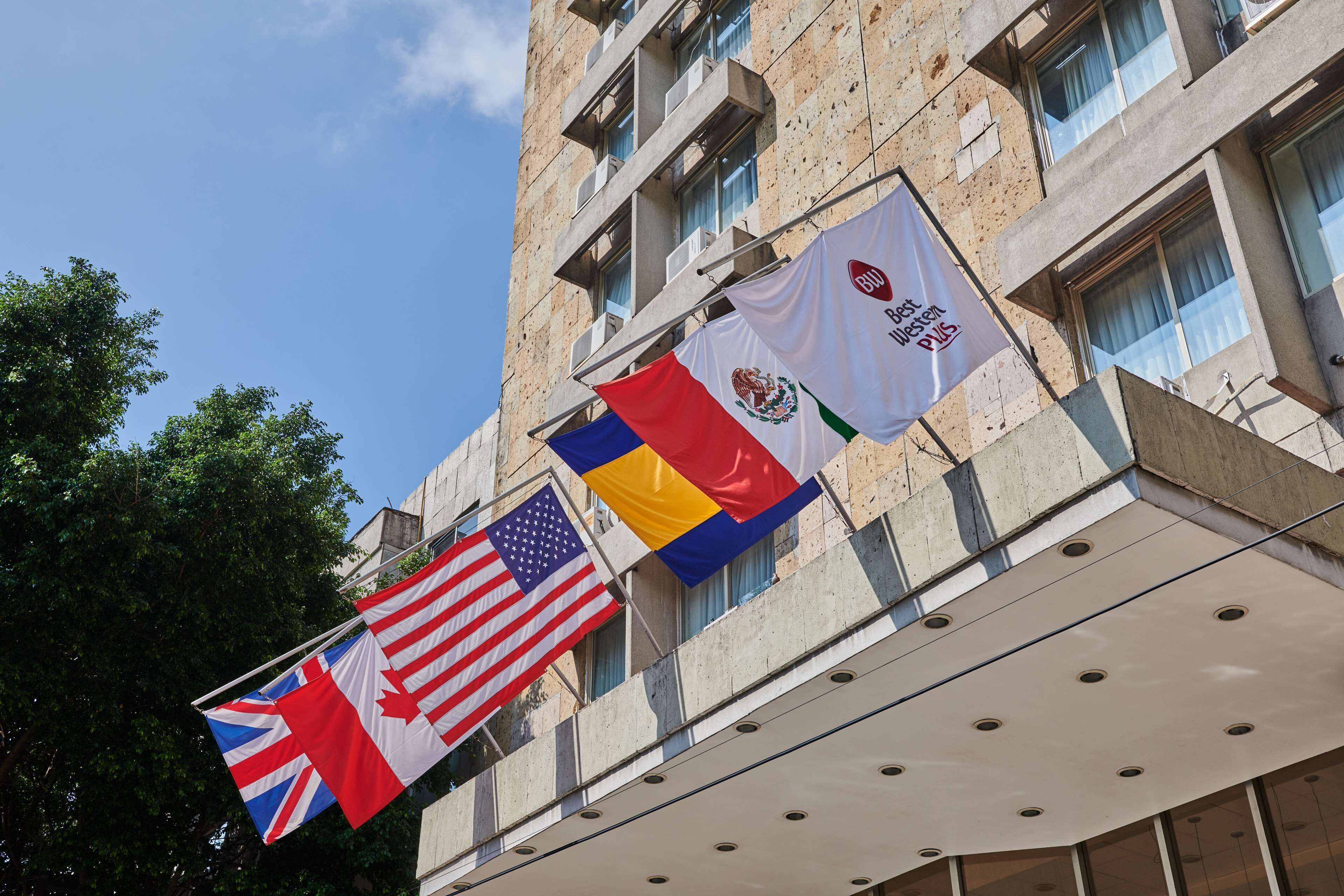 Un edificio con varias banderas, incluyendo las de Estados Unidos, Reino Unido y México, y un letrero que dice 'Best Hotel'.