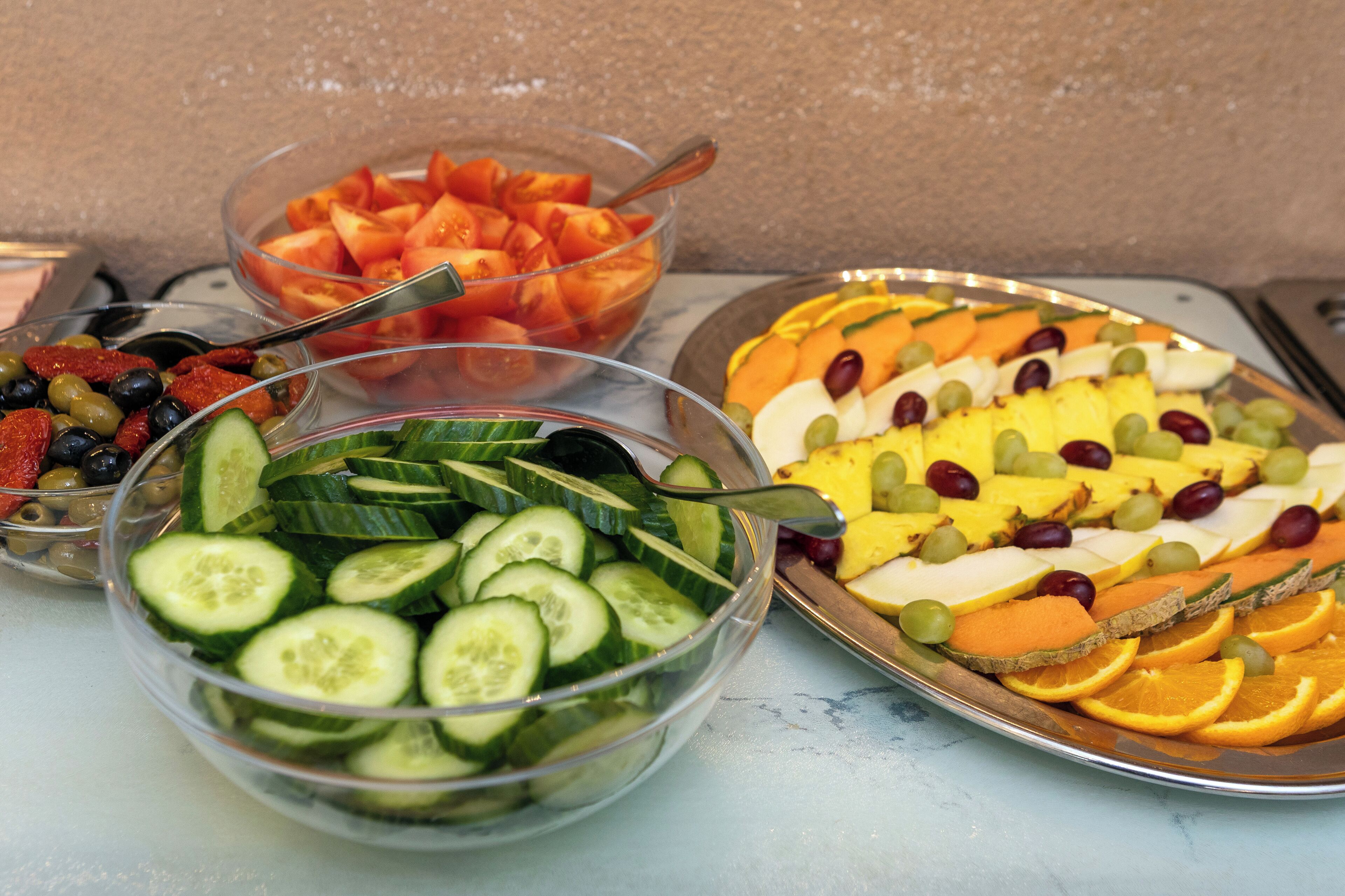 A variety of fruit and vegetable bowls on a table.