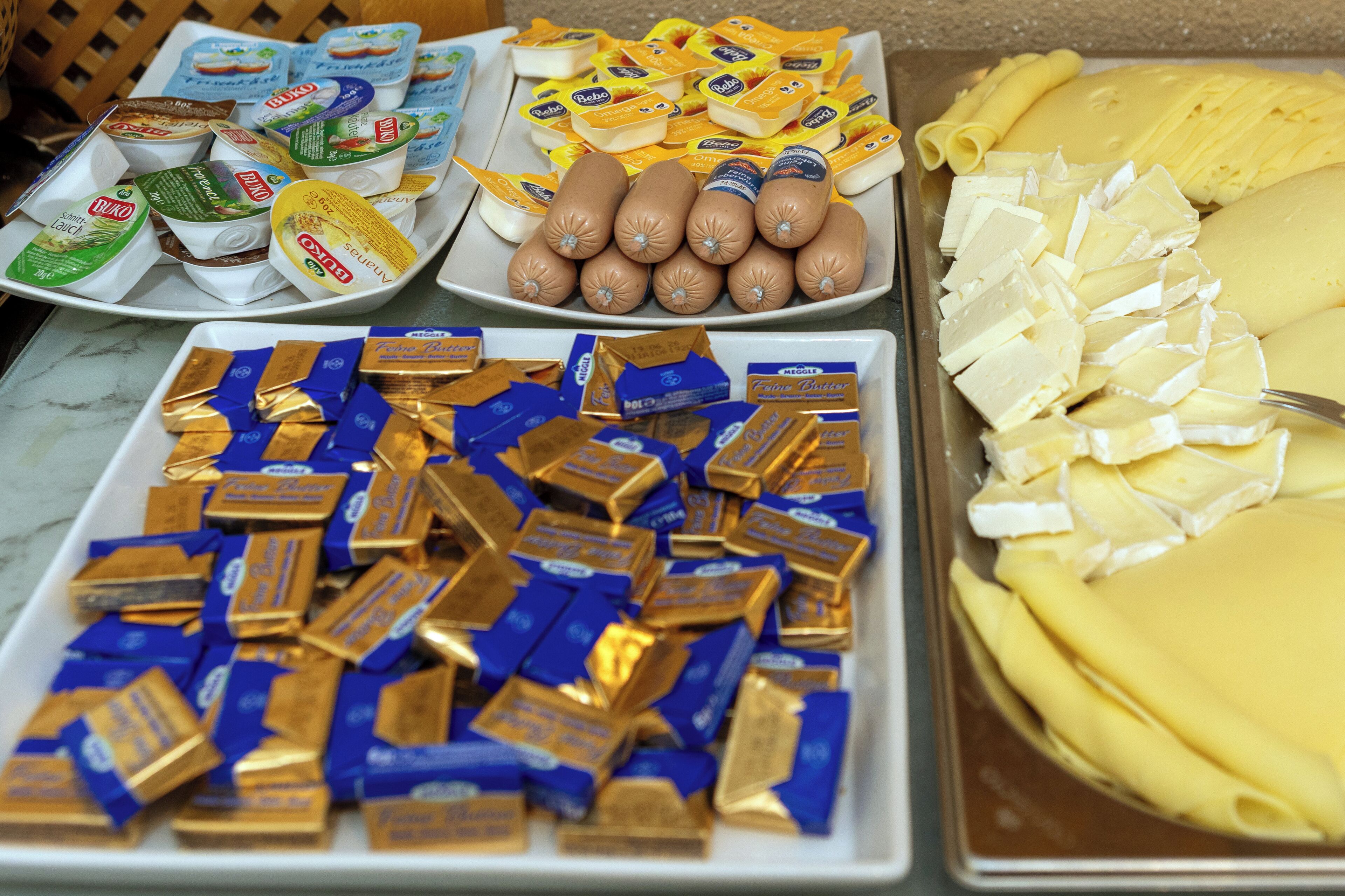 A buffet with various food items including cheeses, sausages, and chocolate bars.