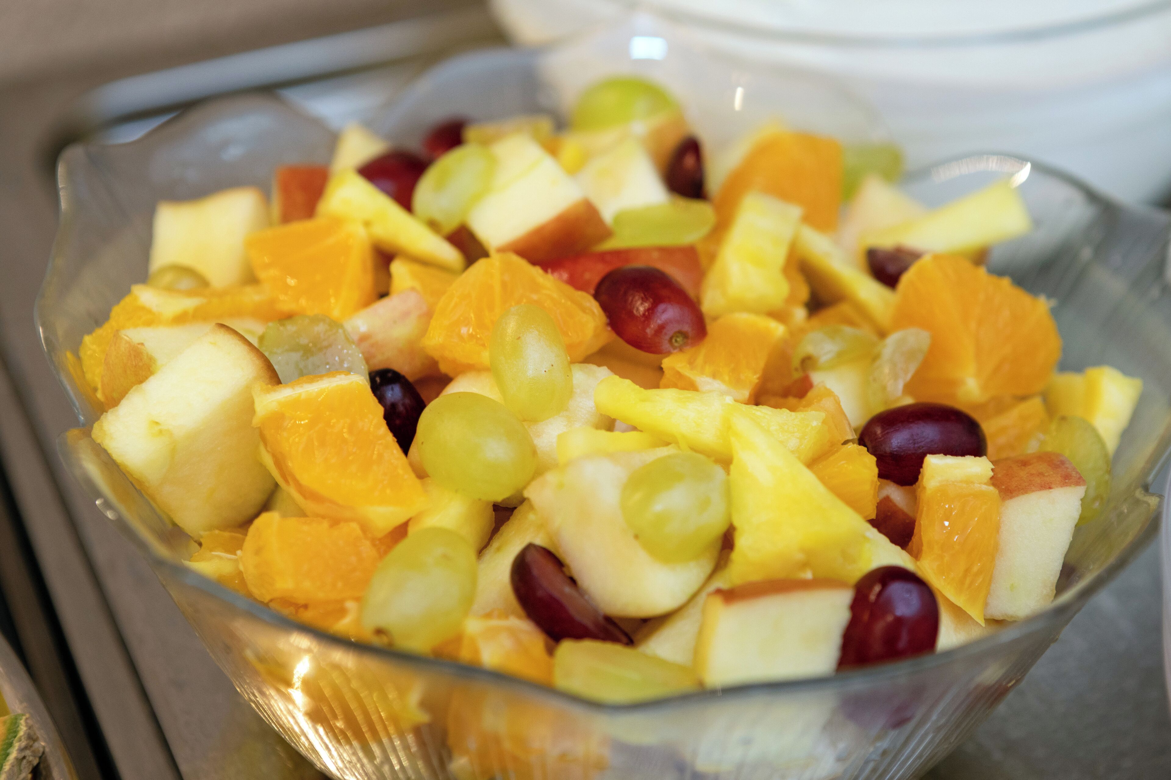 Een glazen schaal gevuld met een verscheidenheid aan fruit.
