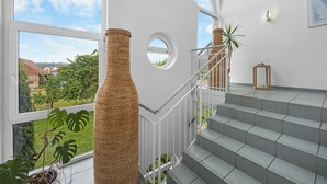 A modern interior with a staircase, large windows, and a view of greenery outside. - Sun Parc Hotel (Ringsheim)