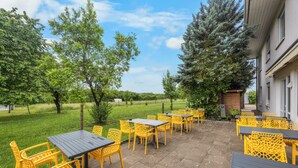 An outdoor patio with tables and chairs, surrounded by trees and a building. - Sun Parc Hotel (Ringsheim)