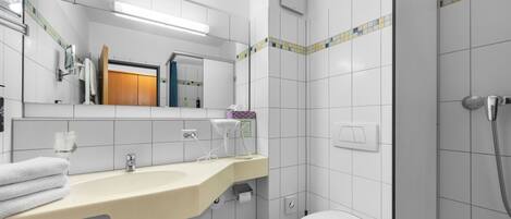 Un baño moderno con lavamanos, espejo, inodoro y ducha.