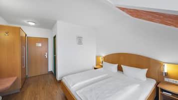Habitación de hotel con una cama grande, cabecero de madera, mesitas de noche con lámparas, un armario de madera y un escritorio pequeño.