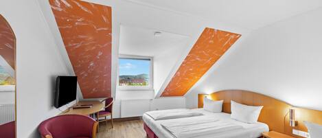 Une chambre d’hôtel moderne équipée d’un lit, d’un bureau, d’une chaise et d’un téléviseur.