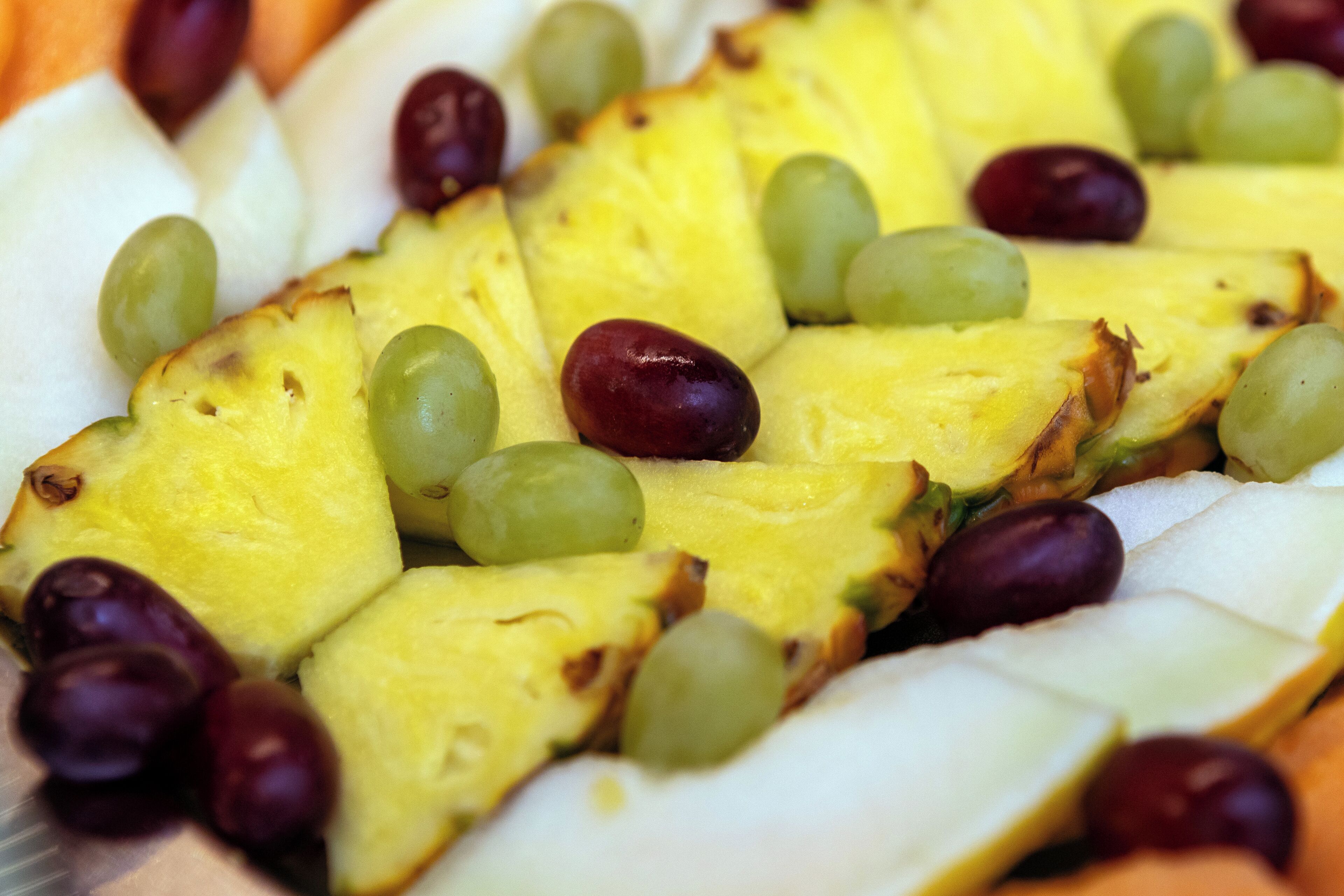 A fruit platter with pineapple slices and grapes.