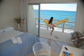 A room with a bed, a chair, a fan, and a view of the ocean. - Rocamar Hotel Panoramico Isla Mujeres (Isla Mujeres)