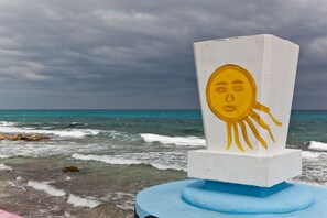 Una estructura blanca y azul con un rostro de sol amarillo en la playa.