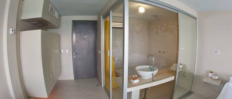A modern bathroom with a glass-enclosed shower, a white sink, and a tiled floor.