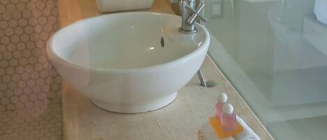 A bathroom with a large white sink, a mirror, and a towel rack.