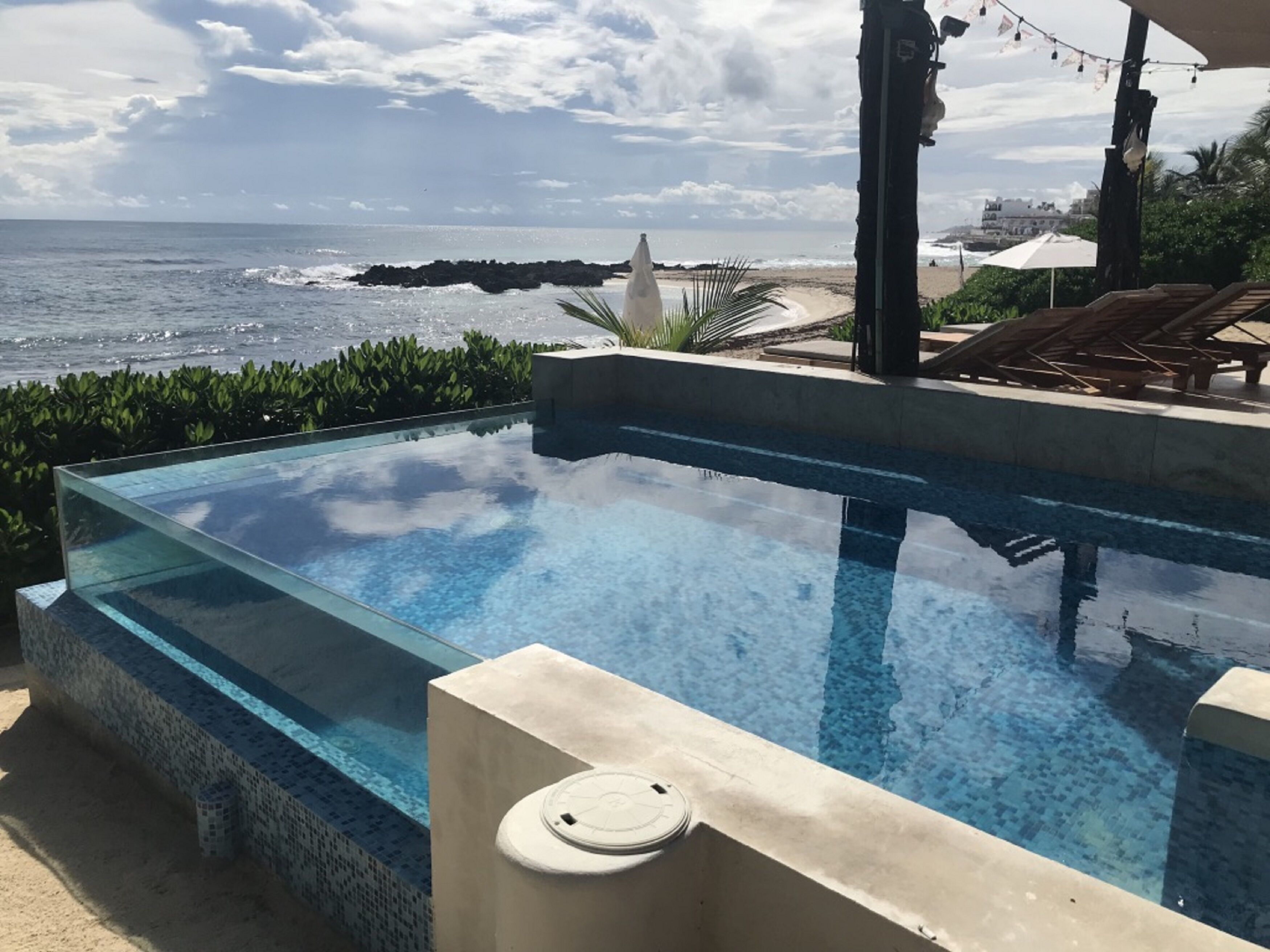A clear infinity pool with a view of the ocean and rocky shoreline.