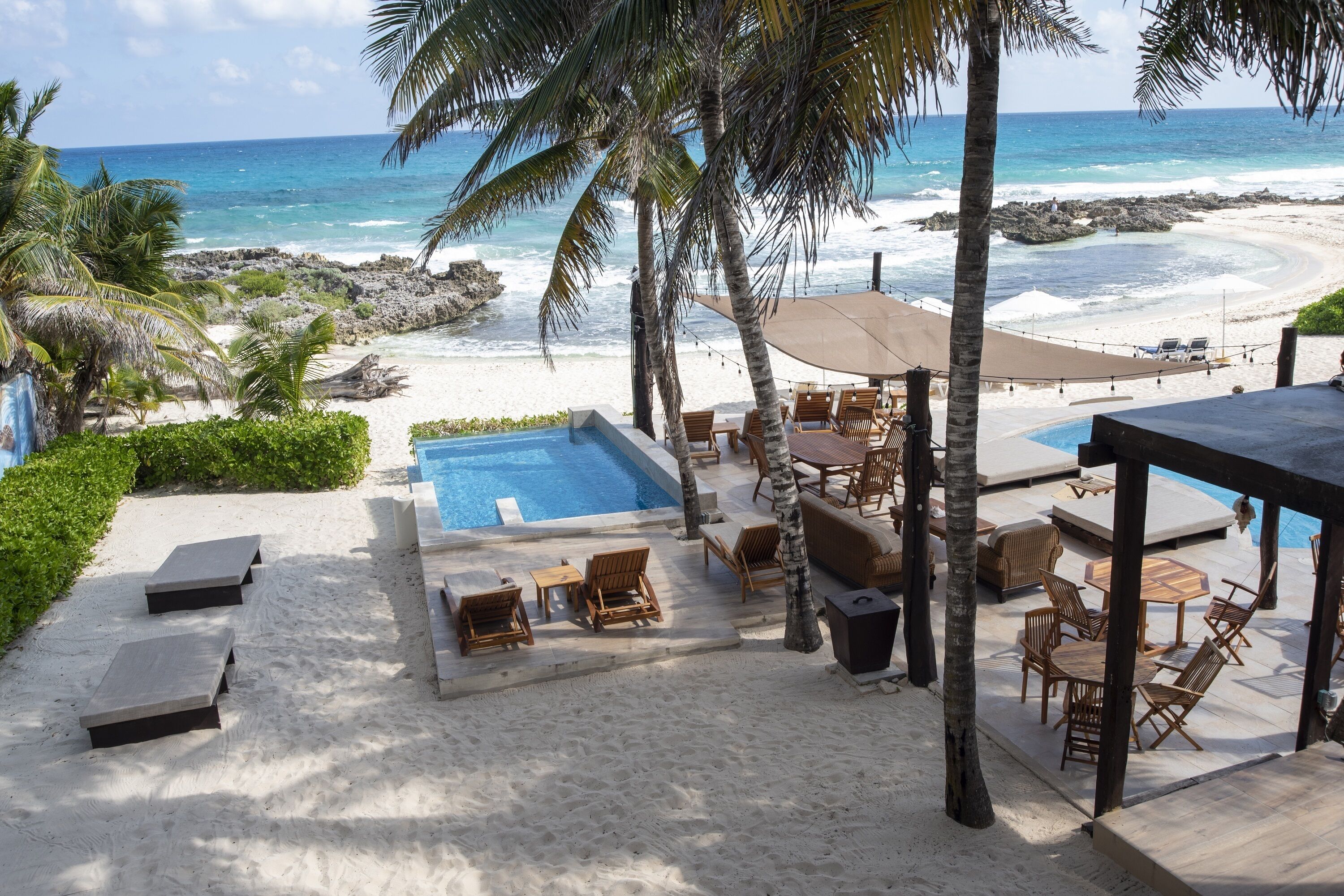 A beachside pool area with lounge chairs, a small pool, and a view of the ocean.