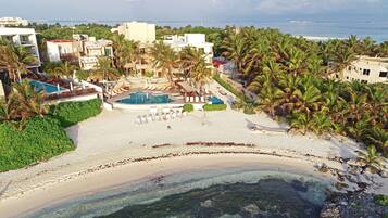 Un resort con piscina, spiaggia e palme.