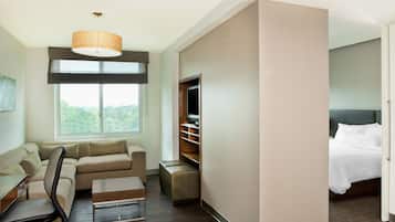 Una habitación de hotel moderna con sofá, escritorio, silla, televisión y cama.
