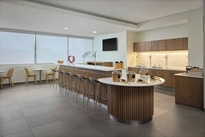 Una cocina moderna con una isla central, taburetes de bar y un amplio ventanal.