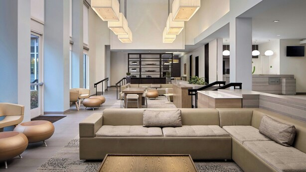 A modern interior with a sofa, chairs, a coffee table, a kitchen area, and a staircase. - Element by Marriott Arundel Mills BWI Airport (Hanover)
