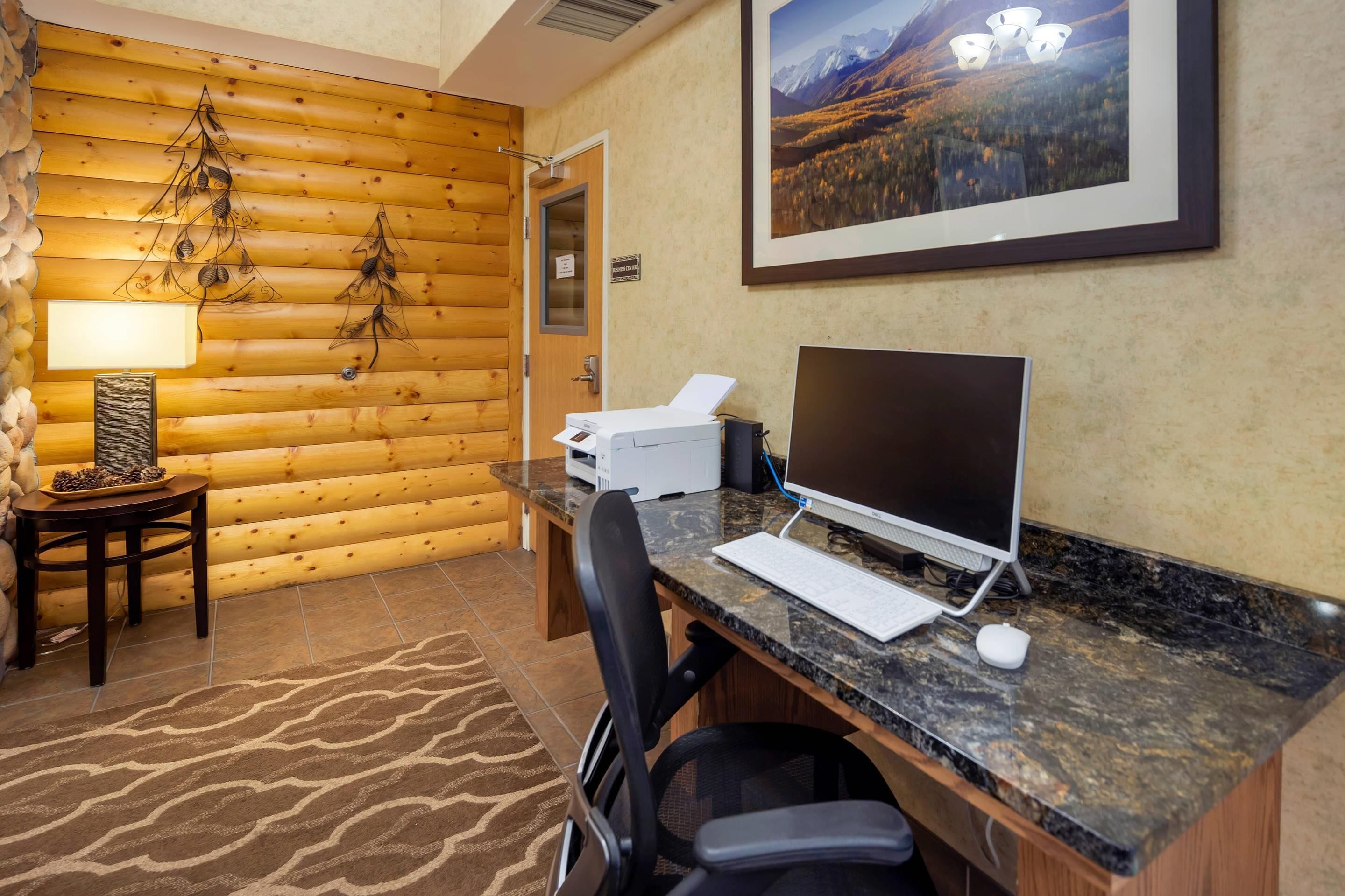 Una habitación con paneles de madera, un escritorio, una computadora y una fotografía enmarcada de un paisaje.