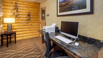 Una habitación con paneles de madera, un escritorio, una computadora y una fotografía enmarcada de un paisaje.