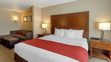 Una habitación de hotel con una cama grande, un sofá, una mesita de noche y una lámpara.