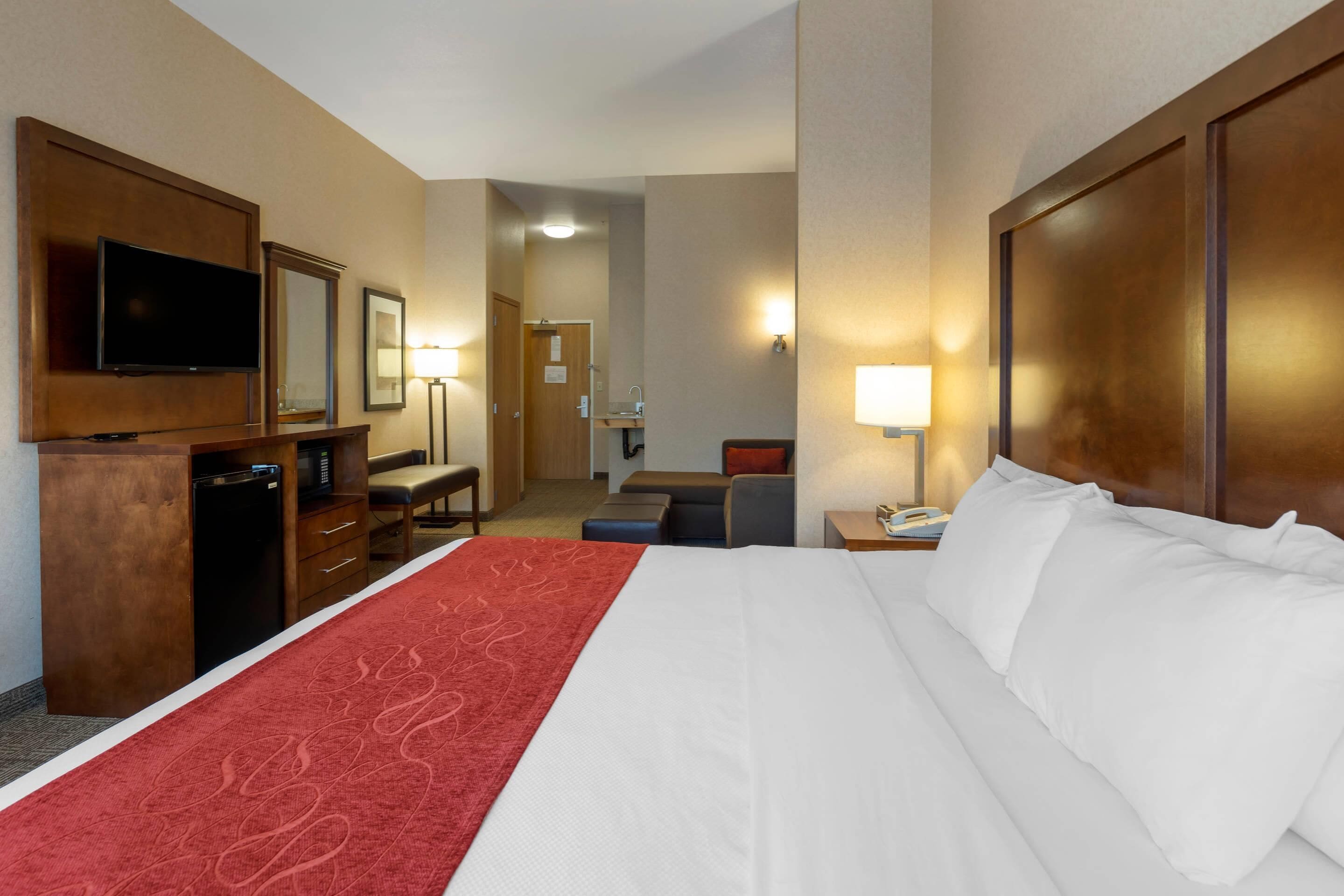 A hotel room with a large bed, a TV, a desk, and a chair.