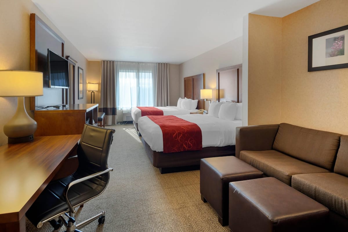 Ett hotellrum med en säng, ett skrivbord, en stol, en soffa och en tv.