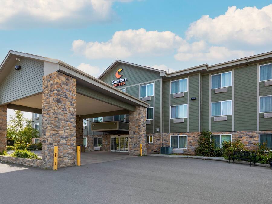 Ein Comfort Suites Hotel mit Steinfassade, zahlreichen Fenstern und einem überdachten Eingang.