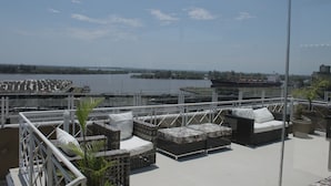 A rooftop terrace with outdoor seating, a view of a river, and a ship in the distance. - Continental Porto Alegre (Porto Alegre)