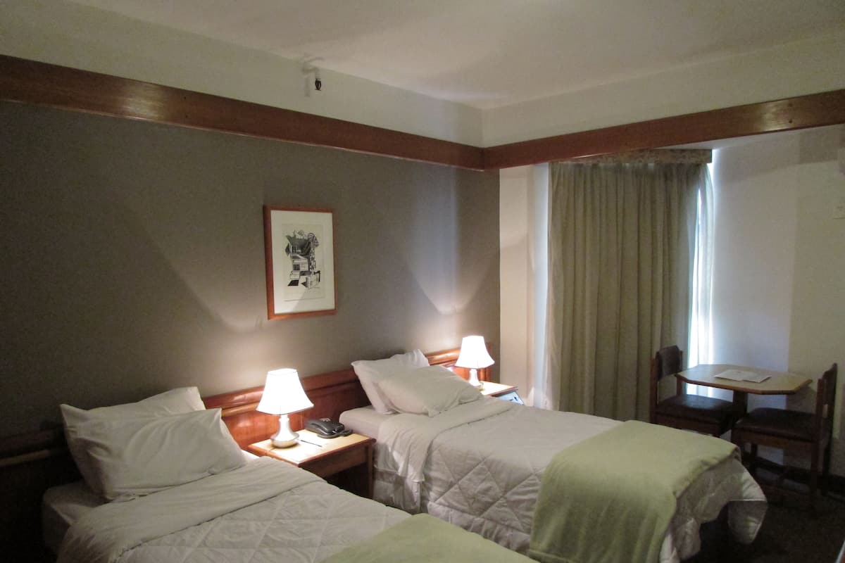 A hotel room with two beds, a desk, and a chair.